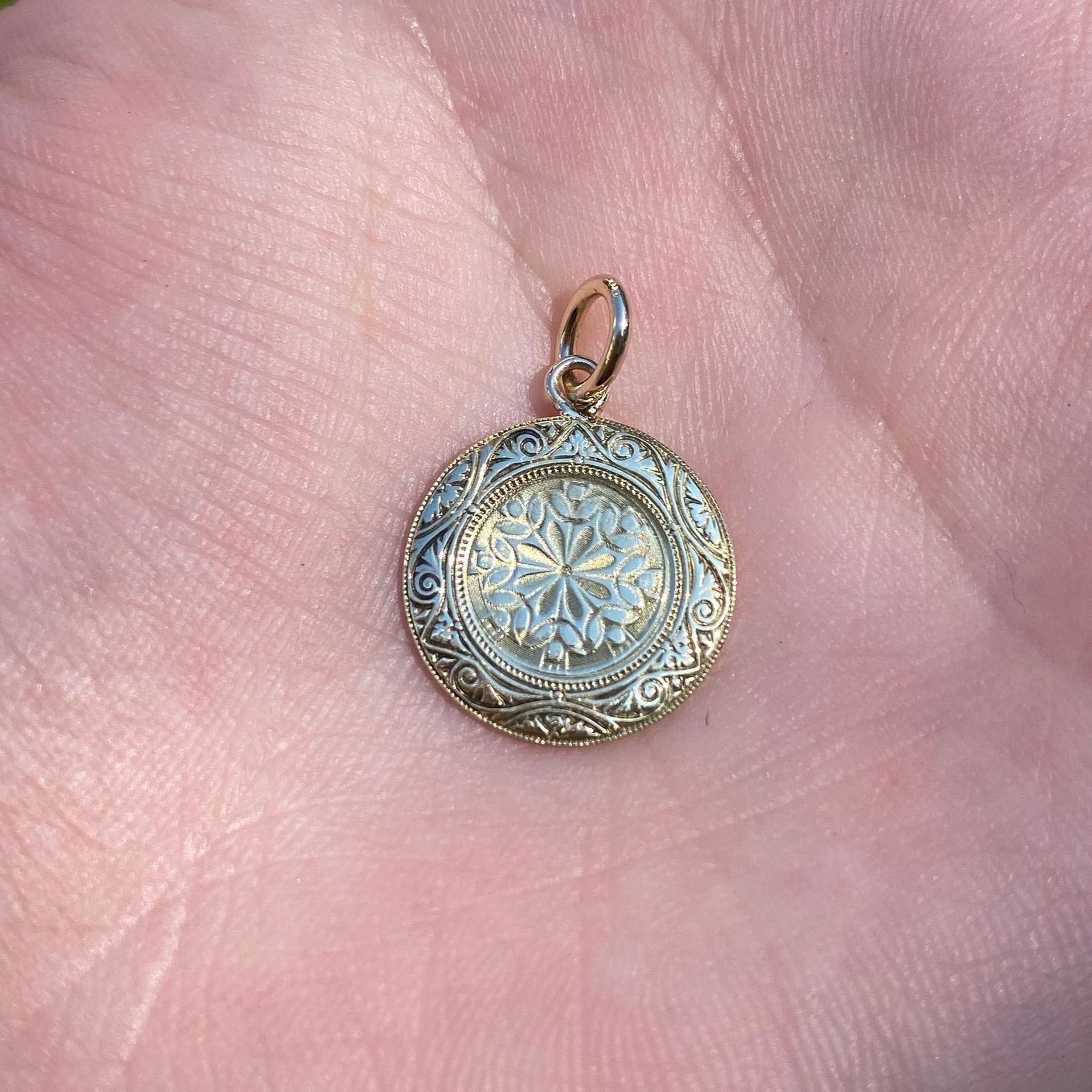Decorative gold and silver pendant on a hand